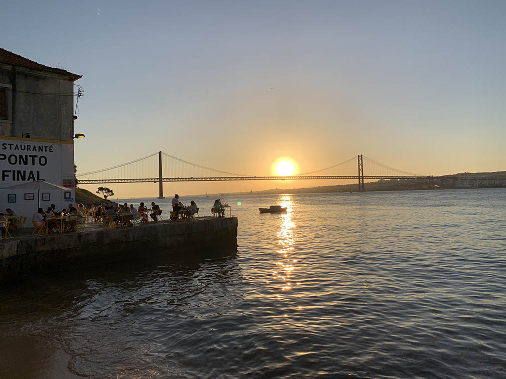 view of the city of Lisbon from the left bank of the Tagus river restaurant tables set up on the river banks