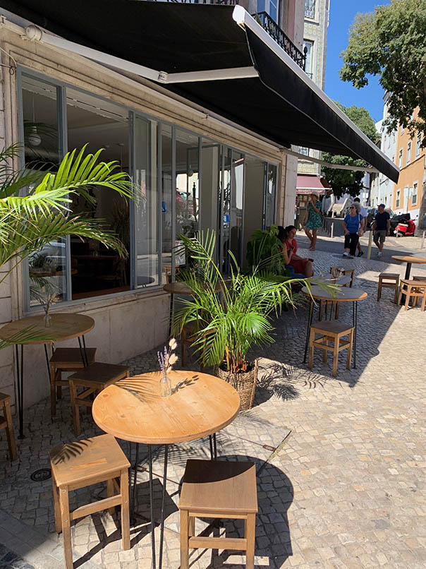 davanti all'Heim brunch café terrazze piante verdi finestre aperte tende nere pieghevoli  