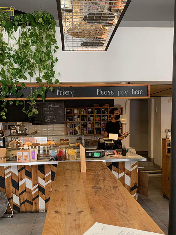 im Inneren des Cafés Mila großen Holztisch vertikal Zähler horizontal mit einem Display von Cookies und Barista in schwarzem T-Shirt