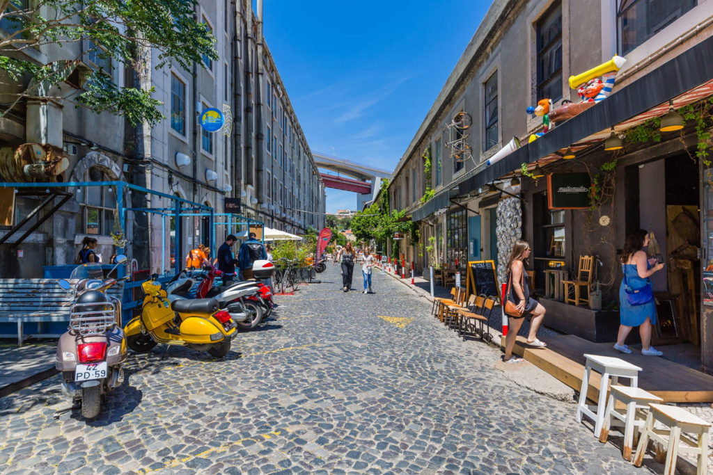 paved pedestrian street of the LX Factory with its shops and a few shoppers and scooters 