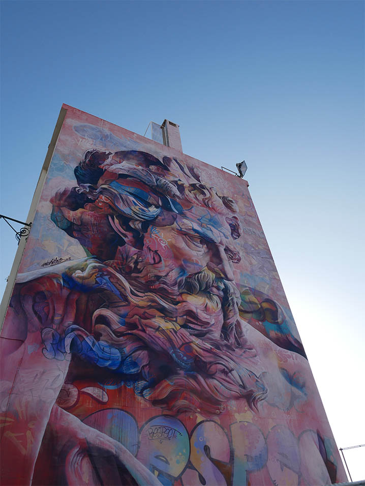 muurschildering van het werk van het duo Pichiavo in San Apolonia Lissabon, voorstellende een Grieks mannelijk standbeeld met tags